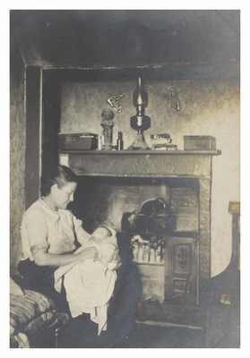 Woman holding baby in front of a cooking range