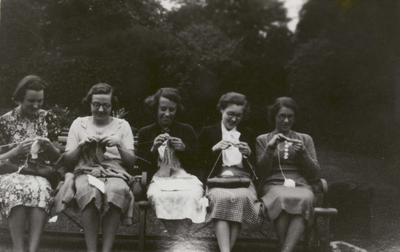 Five women sat on a bench knitting