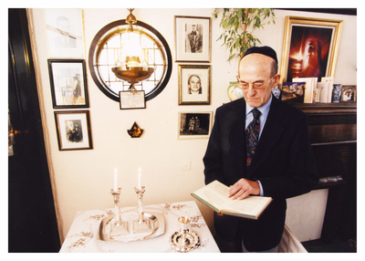 Ernest Levy standing in front of family photos reading