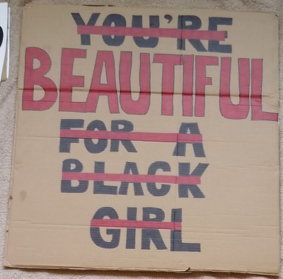 Placard reads 'You're beautiful for a black girl'
