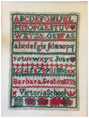 red and green sampler on cream coloured canvas 